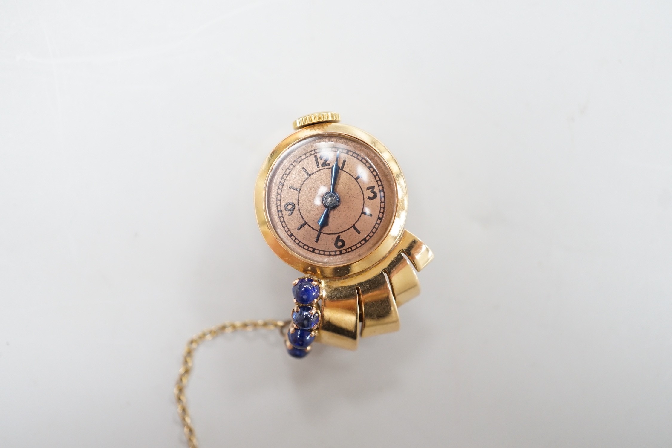 A lady's 1930's/1940's yellow metal and blue cabochon set lapel clip watch, 25mm, gross weight 9.5 grams, with a Richard Ogden gilt tooled leather box.